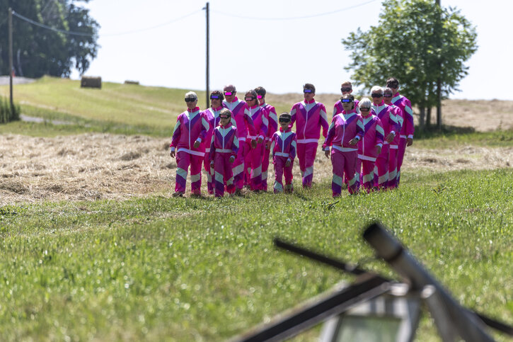 Menschen in pinkfarbenen Overalls wandern in der Landschaft